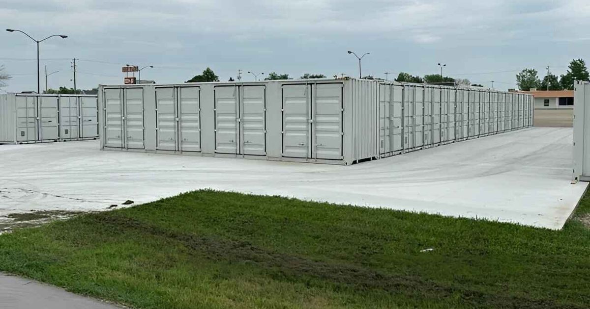 Rows of steel storage containers at ground level on a concrete lot.